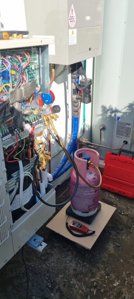 Technician regassing an air conditioning unit